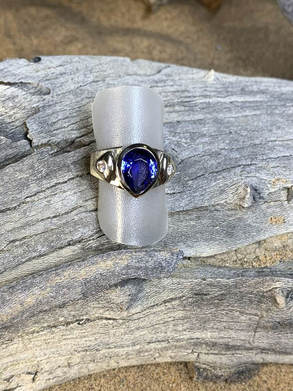 Ring with a pear-shaped violet-blue stone on driftwood