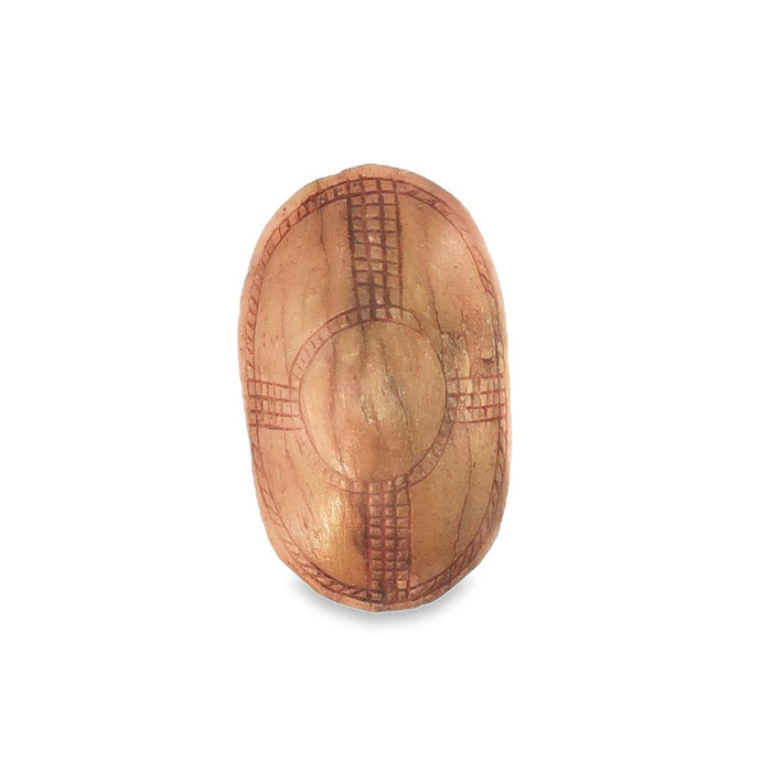 An oval Ekipa carved from makalani palm nut, etched with a cross pattern